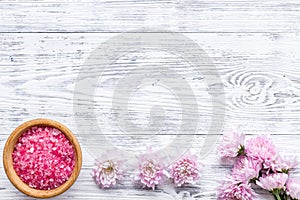 Pink spa salt for aroma therapy with flower fragrance on white wooden background top view copyspace