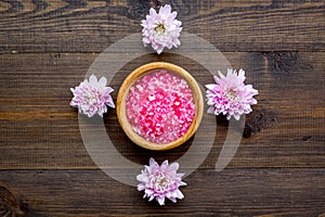 Pink spa salt for aroma therapy with flower fragrance on wooden background top view