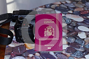 Pink Spanish passport and a digital camera on a table - travel concept