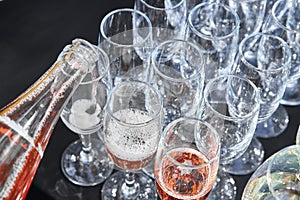 Pink sparkling wine is poured into glasses at a banquet. Top view. Waiter is pouring sparkling wine in flutes.