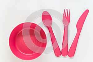 Pink spoon, fork, knife and plate on the white background