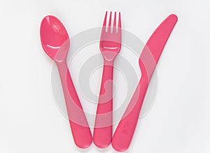 Pink spoon, fork, knife and plate on the white background