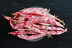 Pink spotty bean pods Phaseolus on a wooden black table