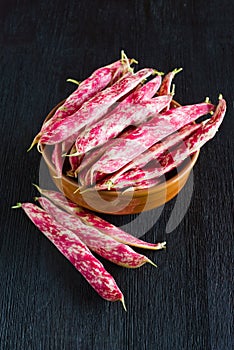 Pink spotty bean pods Phaseolus on a wooden black table