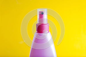 Pink spray cosmetic plastic bottle, isolated on yellow background with copy space. Copy space.