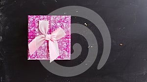 Pink square gift box on chalk board background flat lay