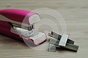 A pink stapler with a pile of staplers