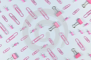 Pink stationery items like paper clips and drawing pins on blue background