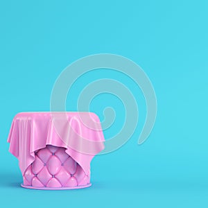 Pink stiched pedestal covered by fabric on bright blue background in pastel colors