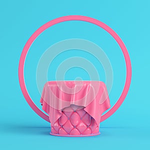 Pink stiched pedestal covered by fabric with round frame on bright blue background in pastel colors