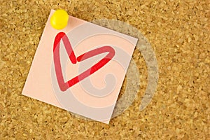 Pink sticker with draw heart on the corkboard