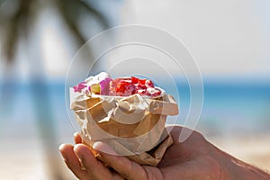 Pink strawberry ice cream in man`s hand in front of beach with p