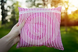 Pink striped pillow holding in hand closeup