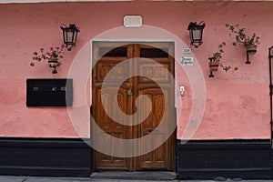 Pink stucco, potted geraniums, 19th century wood doors and wrought iron