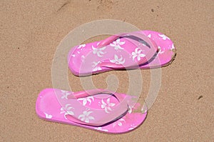 Pink summer slippers on the beach