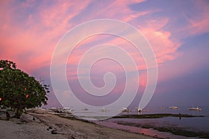 pink sunset and boats on beach on Malapascua Island in the philippines