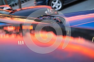 Pink sunset mirrored reflection on a metal car capote photo