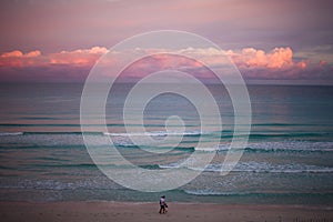 Pink sunset sky. Sea waves gently lapping on the seaside with white sand.