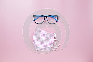 Pink surgical mask plaid and blue glasses on pink backgroud pastel style flatlay topview copyspace