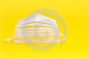 Pink surgical mask for protection against Coronavirus COVID-19 and other contagious diseases. Isolated on yellow background