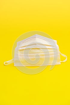Pink surgical mask for protection against Coronavirus COVID-19 and other contagious diseases. Isolated on yellow background