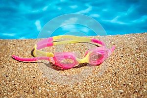 Pink Swimming goggles for kids on the side of a swimming pool