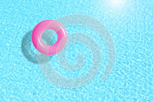 Pink swimming pool ring float in blue water.