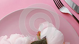 Pink table setting with peony flowers on plate and silverware for luxury dinner party, wedding or birthday celebration