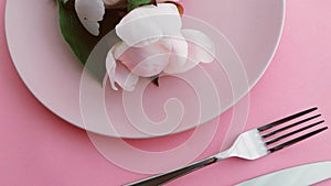 Pink table setting with peony flowers on plate and silverware for luxury dinner party, wedding or birthday celebration