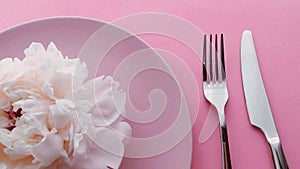 Pink table setting with peony flowers on plate and silverware for luxury dinner party, wedding or birthday celebration
