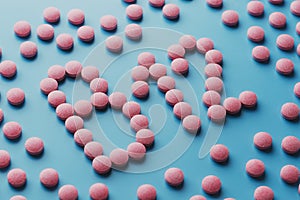 Pink tablets in the form of B12 close-up on a blue background, low contrast