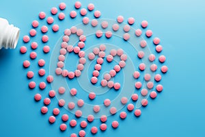 Pink tablets in the form of B12 in the heart on a blue background, spilled from a white can