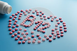 Pink tablets in the form of B12 in the heart on a blue background, spilled from a white can