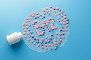 Pink tablets in the form of B12 in the heart on a blue background, spilled from a white can