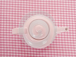 Pink tea pot on table cloth from the top