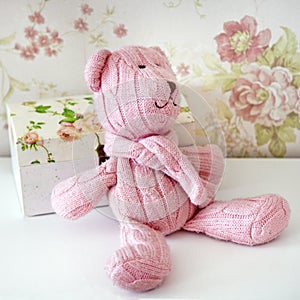 Pink teddy bear knitted sits on a shelf