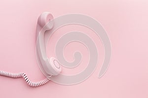 Pink telephone receiver on pink background