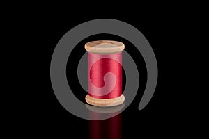 Pink Thread, Cerise Pink Wooden Thread Bobbin isolated on black Background, reflections photo