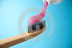 Pink toothpaste on a natural bamboo toothbrush