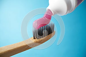 Pink toothpaste on a natural bamboo toothbrush