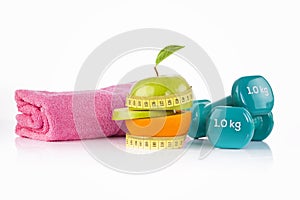 Pink towel, green apple with measuring tape with a pair of blue fitness dumbbells and protein drink