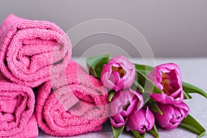 Pink towels in rolls with a bouquet of tulips