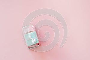 Pink toy retro model car delivering gift box for Valentine`s day on pink background. Volkswagen Beetle on pink background.