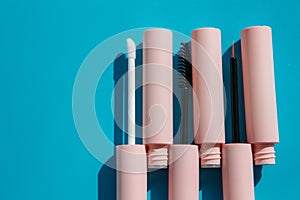 Pink tubes of cosmetics and brushes lie on a blue background.