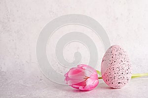 Pink tulip flower and easter egg on light gray concrete backgrond. Easter greeting card