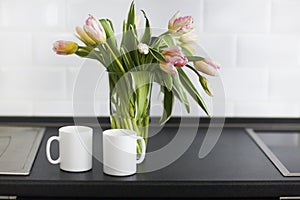 Pink tulips bouquet in glass vase on the kitchen