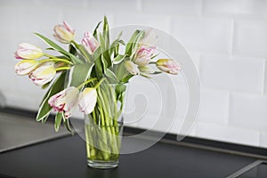 Pink tulips bouquet in glass vase on the kitchen photo