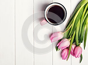 Pink tulips and coffee in a mug on the white table