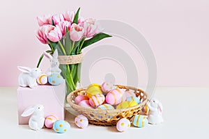 Pink tulips, easter bunnies with colorful eggs in basket