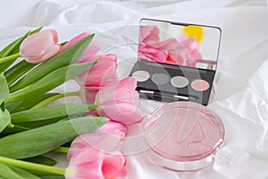Pink tulips, eye shadow palette with mirror and perfume bottle on white background, women cosmetics set